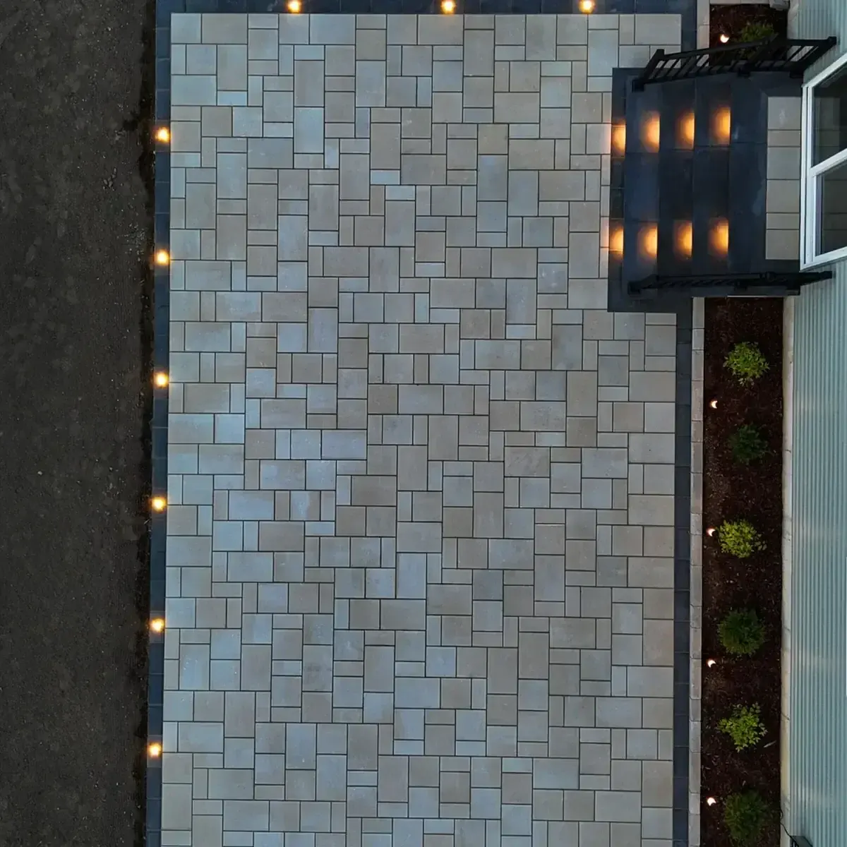 Overhead view of a paver patio edged with landscape lights
