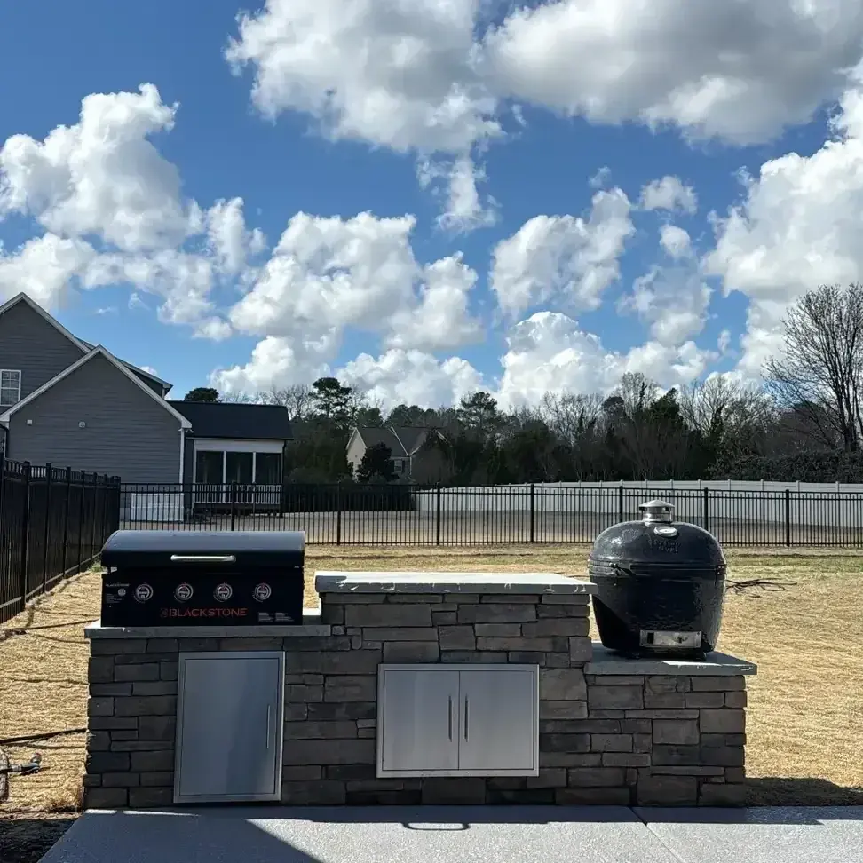 Stone outdoor kitchen island with grill and storage doors under construction