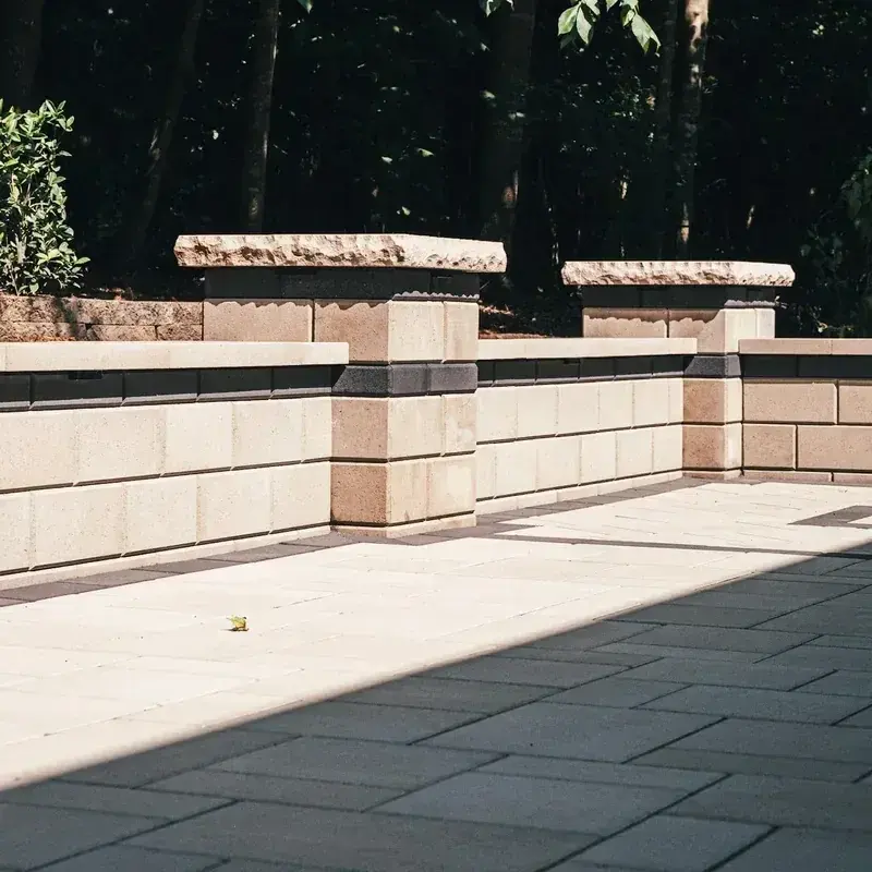 Light paver patio enclosed by a seat wall with stone pillars